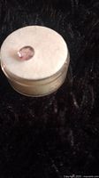 Oval cut pink garnet loose gemstone placed on a white cushion inside a small container.