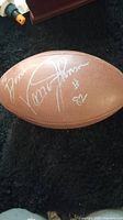 Close-up photo of the football showing Vance Johnson's silver autograph with jersey number #82 and personalization 'To Dixie'