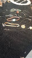 Wide view of assorted leather chokers and necklaces with pendants and charms laid on black fabric.