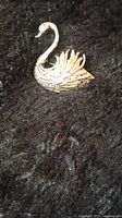 Close-up image of the vintage sterling silver swan bird pin brooch on a dark textured background.