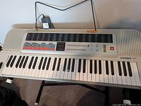 Hohner keyboard on X-style stand with power adapter hanging behind