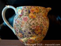 Pitcher with dense floral pattern in yellow and pink hues, rounded shape with handle and spout