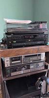 Technics turntable on top of Sony stereo components including 5 CD changer, tape deck, and tuner on wooden stand