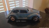 Side view of 1930s light blue metal sedan toy car showing original paint wear and rust spots.