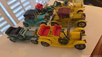 Photo showing six Lesney Yesteryear vintage toy cars arranged on a white surface, displaying color and detailed features.