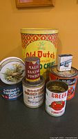 Photo showing main group of 8 vintage tins including Old Dutch Potato Chips (largest) and various smaller tins with vintage branding.