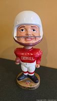 Front view of the 1968 St. Louis Cardinals NFL ceramic nodder with white helmet, red jersey labeled 'CARDINALS', and NFL logo on base with 'St. Louis' name beneath, showing good condition with minor wear on base.