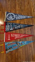 Four vintage space-themed pennants laid out on a wooden floor, showing full designs and colors.
