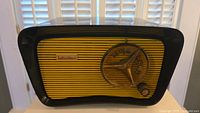 Front view of vintage Hallicrafter radio in black Bakelite with yellow grille and tuning dial.