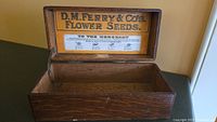 Open view of wooden box showing interior and original paper label advertising D.M. Ferry & Co. Flower Seeds.