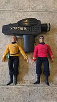 Photo showing both vintage Star Trek figures standing with phaser toy on tile floor.
