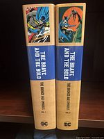 Spines of Volumes 1 and 2 showing title, series line, volume numbers and DC logo.