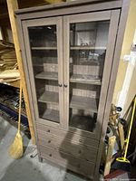 Front view of closed cabinet showing glass doors, drawers and overall structure