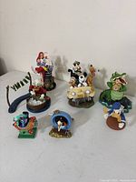 Seven ceramic Disney figurines on white table