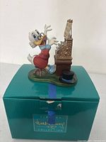 Front view of figurine seated at cash register on original box