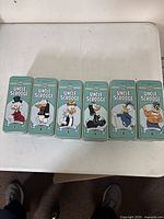 Six numbered tin boxes displayed side by side on table