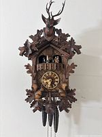 Front view of entire clock showing carving, dial, dancers, weights and chains