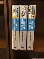 Spines of all three omnibus volumes showing volume numbers and DC logo