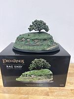 Figurine displayed atop its original packaging box showing front view of Bag End and box artwork