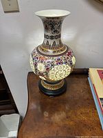 Full view of ceramic lamp showing bulbous body with detailed floral patterns and pierced areas illuminated by light inside.