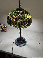 Front view of lamp lit showing stained glass floral shade and base