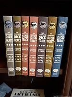 Seven hardcover volumes of 'The Complete Dick Tracy' comic strips by Chester Gould from 1964 to 1976 arranged on a shelf, showing the spines labeled with years and author.
