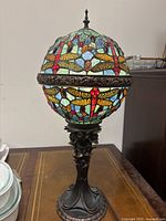 Full view of lamp showing stained glass shade with dragonfly motifs and metal base