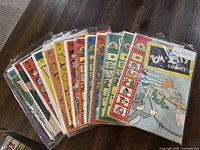 Fan display of 13 bagged and boarded Tom & Jerry comic issues laid out on a wooden surface