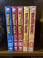 Spines of all five volumes on shelf in sequential order