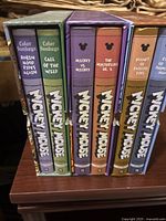 Six hardcover Mickey Mouse comic books in slipcases with titles on spines.