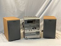 Overall view of the Sony Micro Hi-Fi system showing the central unit flanked by the two speakers, displaying the wood finish and fabric grills.