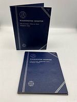 Two closed blue Whitman Washington Quarter Collection albums upright and lying flat.