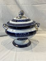Front view of the covered serving dish with lid on, showing the blue and white porcelain design and gold accents.