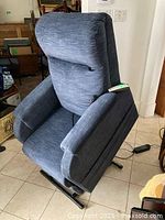 Front view of blue upholstered recliner chair on tiled floor.