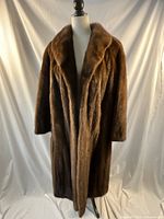 Full view of full length brown fur coat on mannequin, showing coat length and shape