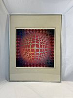 Full view of framed modern abstract print with geometric 3D sphere pattern in red and purple hues.