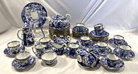 Wide view of entire Blue Mikado tea and coffee service arranged on white drape