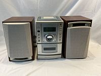 Front view of the Sanyo micro component system DC-DA300 with two wooden speakers, beige grilles, placed side by side on a white cloth surface.