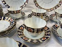 Close-up of the teacup and saucer showing the scalloped edges and detailed Imari border pattern with gold accents.