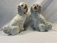 Front view of both white ceramic spaniel figurines showing overall condition and detailing