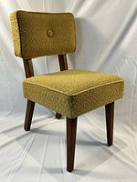 Front angled view showing the textured yellow-green bouclé upholstery and the dark tapered wooden legs of the child's chair.