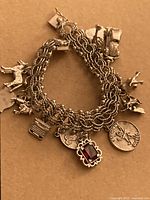 Sterling silver charm bracelet with multiple detailed sterling charms on a brown background.