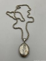 Full view of rope chain and oval locket arranged on white background