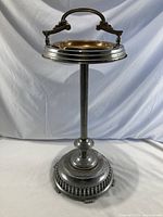 Full-height front view of ashtray showing base, stem, top ring and handle