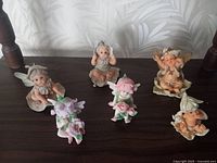 Top view of the six fairy baby figurines arranged on a shelf, showing various poses and colors