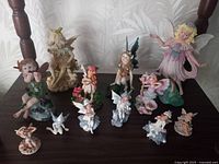 All fairy figurines arranged on a dark wooden surface under soft lighting, showcasing design detail and size variety.