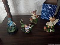 Four fairy figurines on shelf including two with blue boxes