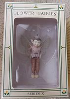 Front view of the fairy figurine in packaging, showing the figure with wings and detailed costume.