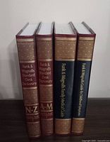 Four hardcover Funk & Wagnalls books standing upright showing spine titles and volume markings.
