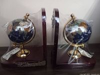 Photo of the pair of globe bookends wrapped in plastic, showing the front and side views.